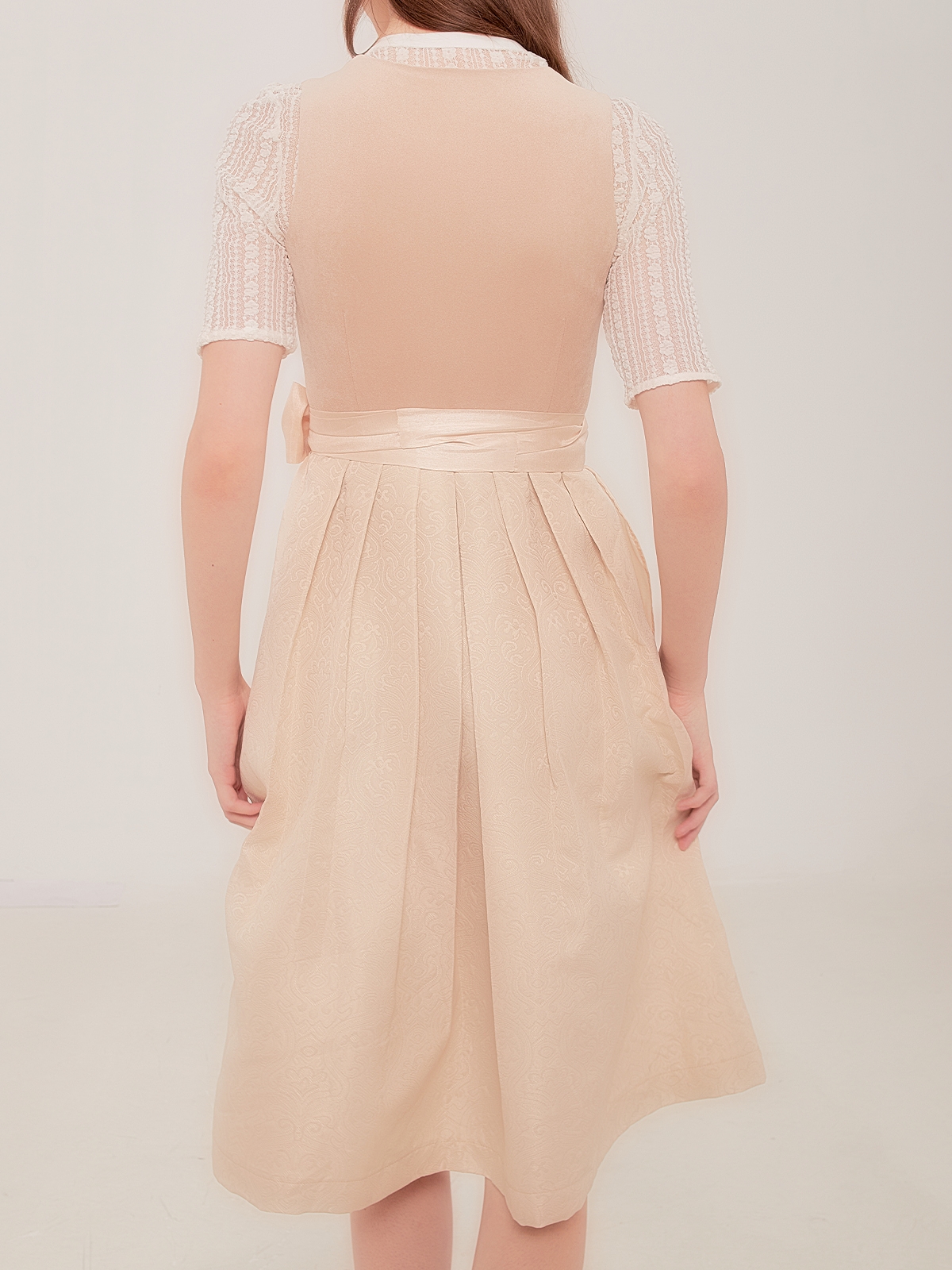 Ein beiges Dirndl mit traditioneller Schürze und Spitzenbluse